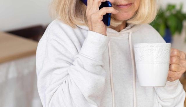 woman holding phone and cup of coffee