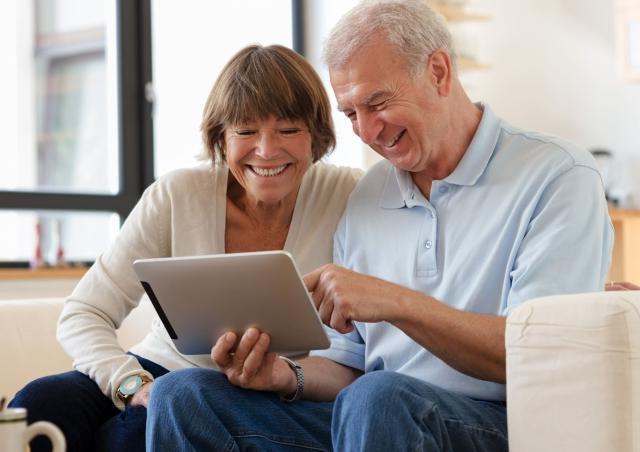Older couple smiling at their tablet.